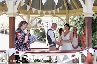 Picture from a wedding - celebrant reading, bride and groom smiling